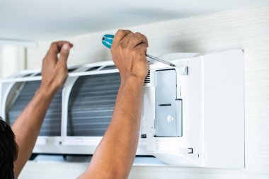 Evde ya da ofiste teknisyenlerin elinde bulanık tornavida bulunan klimaya seçici odaklanma.