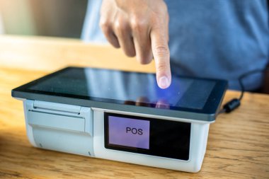 Kasiyerin eli, kasadaki müşteriyi suçlamak için POC ekranına dokunuyor. Kafede ödeme terminali.