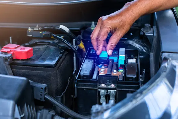A mechanic is opening the cover of a car\'s electrical system control box. Car fuse box.