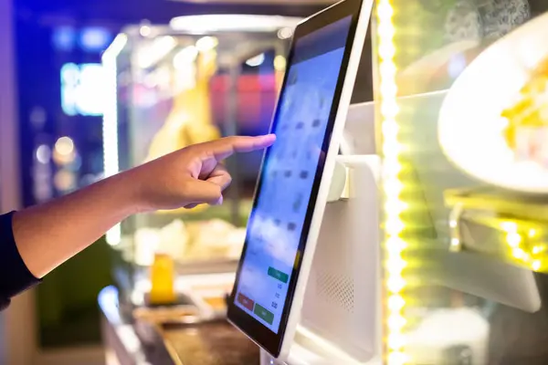 Selective focus to customer's hand is touching a touch screen to order food and pay electronically. Digital order concept.
