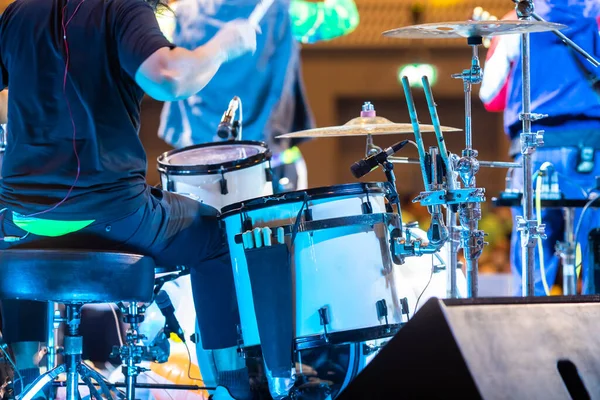 Selective focus to drum set and drummer with blurry music band in concert. Music concert background.