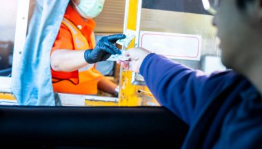Sürücünün, ekspres yol parasını ödemesi için seçmeli odak noktası. Adam otoyol gişesi girişi için kasiyere para ödüyor. Yol boyunca el ödemesi ekspres geçiş ücreti. Hızlı ödeme yolu.