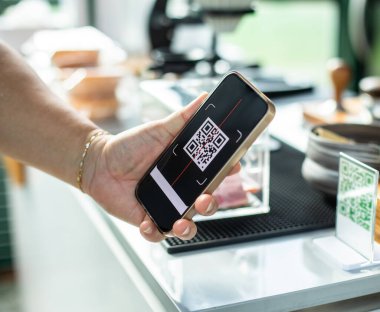Akıllı telefonu tutup etiketteki QR kodunu taramak için seçici odak noktası. Müşteri el yapımı ödemeler para olmadan dijital ödeme üretmek için kabul edilir. Qr kod paymant terminali.