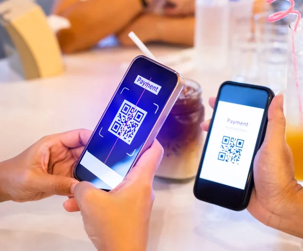 Hand using smart phone to scan QR code on tag with blurry soft drink  and customers in cafe or restaurant to accepted generate digital pay without money. Qr code payment concept.