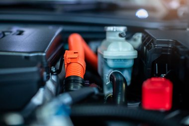 Melez otomotiv motor odasındaki kablo bataryası ve radyatör seviyesindeki ölçüm tankına seçici odaklanma. Yeni teknoloji motorunun bir parçası.