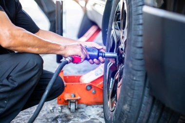 Araba üzerinde tekerlek değiştirmeye çalışan profesyonel araba tamircisinin elindeki hava anahtarına seçici odaklanma. Pnömatik anahtar araçları.