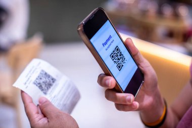 Kadın, internetten ödeme yapmak için ödeme makbuzundaki QR kodunu tarıyor. Qr kod ödeme kavramı.