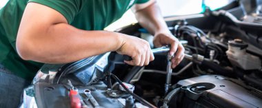 Motoru tamir eden profesyonel bir tamirci, bir araba motoru atölyesini İngiliz anahtarı, araba servisi ve bakım servisi ile tamir ediyor. Otomobil servisi.