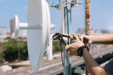 Wi-Fi sinyal çanak sistemini yüklemek için bağlanan fındıkları sıkan mühendislerin ellerine seçici odaklanma.