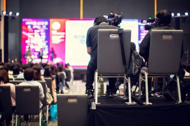 Bulanık video kamera seti olan kameramana seçici odak, konferans salonu veya seminer etkinliğinde hoparlör ve seyirciye kaydediliyor. Sergi fuar merkezi. kitle iletişim aracı kavramı.