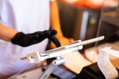 Kasiyer personelinin bulanık eliyle tabletin kenarına seçici odaklanma, kafe veya mağaza tezgahındaki müşterilerden emir almak için.