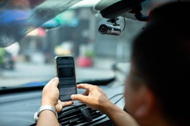 Araba mobese kamerasının video kaydedicisine odaklanın. Teknisyen yola güvenlik için kameralı bir araba ve akıllı telefon kuruyor. Acil durumlarda kanıt kaydetmek için arabadaki konsol kamerası..