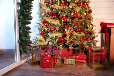 Dekorasyonlu Noel ağacı ve hediyelerle dolu bir oturma odası. Akşamları pırıl pırıl çelenkleri olan Xmas ağacı. Evde Noel. Yeni yıl kış evi dekorasyonu. 
