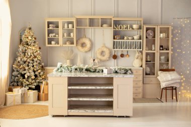 Süslü Noel ağacı ve hediyeli şık bir mutfak. Kış dekorunda ahşap mutfak. Mutfak gereçleri ve tabaklar rafta. Yemek odasındaki mutfak adası. Mobilyalarla dolu rahat bir Xmas mutfağı
