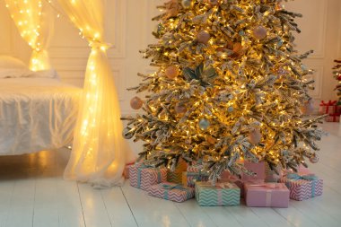 Akşamları oturma odasında parlayan Noel ağacı. Işıkları parlak çelenkleri ve hediyeleri olan Noel ağacı. Xmas dekorasyonlu şenlikli iç tasarım oturma odası. İç dizayn odası.. 