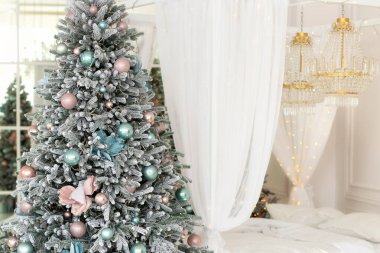 Beyaz perdeleri akan beyaz yataklı modern beyaz yatak odası ve pırlanta kristalleri parlayan kristal avize. Şenlikli noel ağacı. İç dizayn odası..