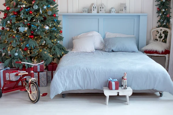 Concept new year and winter holidays. Scandinavian room style. Interior design bedroom. New year winter home interior decor. Bright bedroom with decorated christmas tree and comfortable bed.