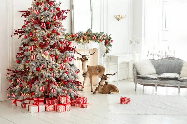 圣诞树 灯火辉煌的花环和礼物 风格别致的白色客厅内部装饰圣诞树 壁炉和沙发与枕头 圣诞节在家里 新年家居装饰 — 图库照片