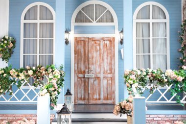 Bahar tasarımı evi çiçek açmış ve merdivenlerde süsleme fenerleri var. Paskalya için dekore edilmiş eve giriş merdivenleri. Evin ahşap verandasında farklı çiçekler var. Yazlık evin terası. 