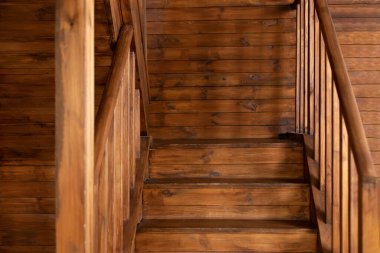 Modern staircase with wooden steps in flat. Wooden Stairway goes up. Country wooden house is spacious on two levels. Room with wooden stairway leading to second floor of modern flat. 