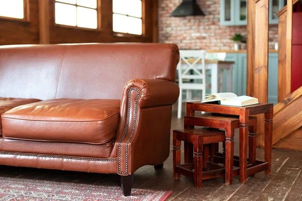 Comfortable Brown eco leather couch standing in living room with modern interior design and wooden coffee table. Modern design of room in loft style.Fragment of the interior of a country house.