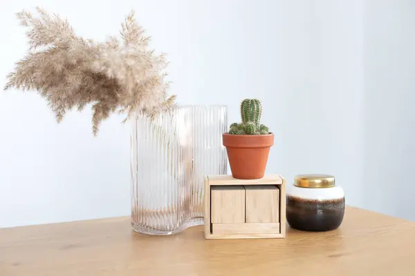 Modern interior workspace with cactus, vase with dried flowers, blank blocks wooden calendar. Indoor succulent plant in ceramic pot. Desk with stylish decoration at home, copy space.
