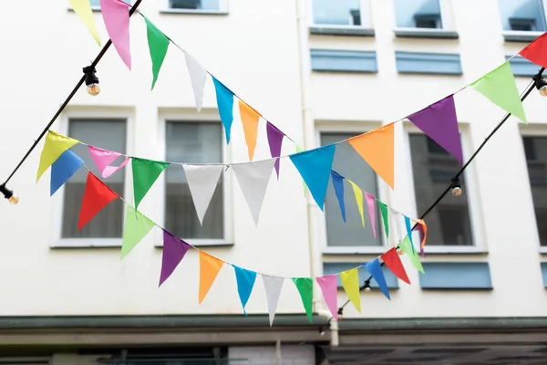 stock image Flags multicolored birthday decorations hanging on street. Colorful bunting flags hanging in park. Garden party decoration. Wedding decor. Decorative flags of textile for holiday decor hang on rope 