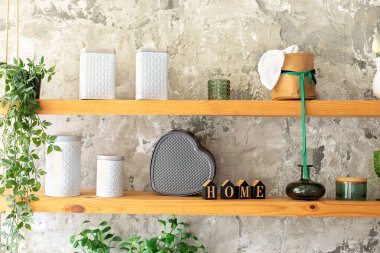 Seramik kavanozlar, tabaklar, ev bitkisi ve mutfaktaki ahşap raflarda rahat bir dekor. Açık mutfağın iç kısımları çok şık. Tabak rafında bir sürü kap var. Dairenin içinde İskandinav minimalist tasarımı