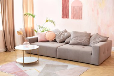 Rahat kanepe ve mobilyalarla modern oda içi. Şık gri kanepe, yastıklar ve modern İskandinav evinde kurutulmuş çiçeklerle dolu kahve masası olan rahat bir oturma odası iç tasarımı.. 