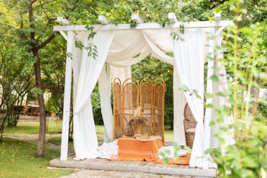 Beyaz perdeleri akan yaz çardağı. Düğün boho dekorasyonu. Hasır mobilyalarla dışarıdaki terası dekore et. Arbour 'un dış tasarımı. Rattan tavus kuşu koltuğu ve dekoratif katlama ekran ayırıcısı