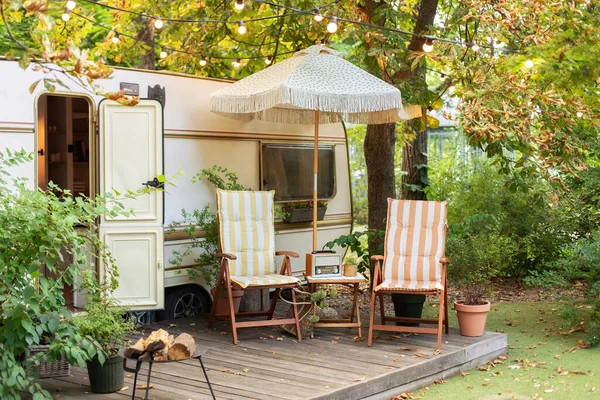 stock image Backyard with RV house with garden furniture. Two deckchairs near outside caravan trailer. Cozy Campsite on caravan or camper van in forest. Trailer of mobile home stands in garden in camping. 