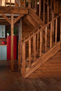 Modern staircase with wooden steps in flat. Wooden Stairway goes up. Country wooden house is spacious on two levels. Room with wooden stairway leading to second floor of modern flat. 