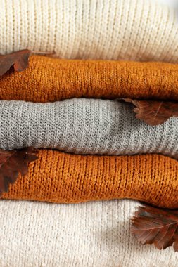 Çeşitli şekillerde örülmüş. Sıcak örülmüş süveter yığınının desenini kapat. Sıcak sonbahar ya da kışlık kıyafetler. Geçmişi. Organik süveterler ve ekose kumaşlar. Bir yığın kaşmir elbise.