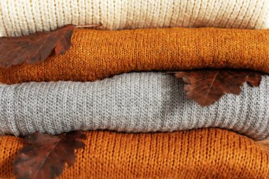 Çeşitli şekillerde örülmüş. Sıcak örülmüş süveter yığınının desenini kapat. Sıcak sonbahar ya da kışlık kıyafetler. Geçmişi. Organik süveterler ve ekose kumaşlar. Bir yığın kaşmir elbise.