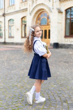 Kitapları olan liseli kız. Okula dönelim. İlköğretim okulunun kıvırcık saçlı genç ve tatlı kızı. Dersler başlıyor. Okul binasının yakınında küçük bir kız.. 