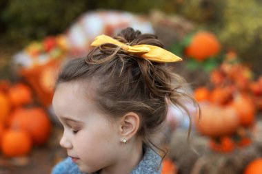 Sarışın küçük kız dalgalı saçlarını şık bir saç fiyongu ile düşük bir demet halinde topladı. Arka ve yan görüş yakın. Fiyonklu saç topuzu. Saçına sarı şifon fiyonk takmış küçük bir kızın portresi..