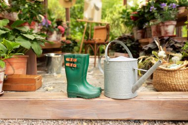 Yeşil lastik çizmeler, sulama kutusu ve hasır sepet. Evin terasında rahat bir dekor. Serada bahçe botları. Ahşap verandada, evin önünde yağmur botları. Arka bahçede çizmeler var.. 