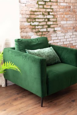 Zarif modern oturma odası. Çatı katı tarzı. Tuğla duvarın yanında yeşil koltuk var. İç tasarım orta çağ tarzında..