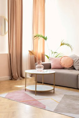 Modern İskandinav evinde gri kanepe, yastıklar ve kurutulmuş çiçeklerle dolu kahve masası olan oturma odası iç tasarımı. Duvarında makrome ve şık mobilyaları olan modern bir oda.