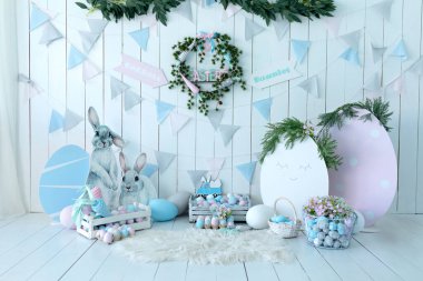 Renkli Paskalya odası dekoratif biblo tavşanlı iç tasarım. Bir sürü renkli Paskalya yumurtası ve havuç dolu sepetler! Beyaz duvarda bayram bayrakları ve şenlikli çelenkler. Bahar tarzında çocuk odası. 