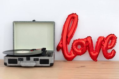 Aşk şeklinde kırmızı folyo hava balonu ve beyaz arka planda plak çalar ve vinil disk. Sevgililer Günü ya da düğün, bekarlığa veda partisi, doğum günü süsü. İç tasarım odası.