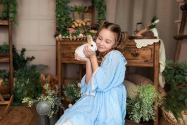 Küçük mutlu kız, sevimli, tüylü bir paskalya tavşanı tutuyor. Bunny ile arkadaşlık. Sevimli Çocuk ve Hayvan. Küçük Çiftçi. Hayvan sevgisi konsepti. Kapalı portre genç gülümseyen kız tavşanla oynuyor. 