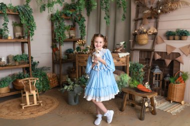 Mavi elbiseli genç kız Paskalya tavşanı ile oynuyor. Bir çocuk gerçek bir tavşanı kollarında tutarken Paskalya 'nın iç odasının arka planına yaslanır. Sevimli Çocuk ve Hayvan. Hayvan sevgisi konsepti