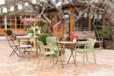 Masaları ve tahta sandalyeleri olan boş bir kafe. Lokantanın klasik dış yüzeyi. Avrupa 'daki kahve dükkanı için mobilya. Bahçede kafe masaları olan bir sokak.