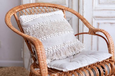 Tavus kuşu sandalyeli iç tasarımı olan modern boho odası. Yastıklı hasır tahta sandalye. Eko mobilyalar, doğal mobilyalar. Yastıklı hasır koltuk. Evdeki tekstil. Samimi dekorasyon