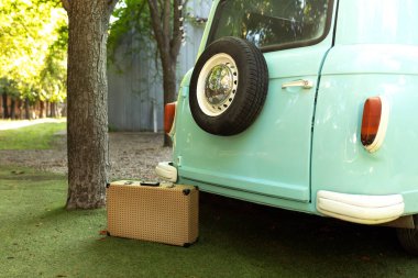 Bahçedeki eski mavi otobüsün yanında antika bir bavul. Seyahat kavramı ya da aile tatili için piknik için şehir dışına seyahat. Bavullu eski bir ışınlama aracı. Kamp yaparken naneli mini otobüs.. 