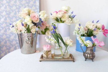 Eski vazolarda birçok farklı çiçekli masa: güller, laleler, şakayıklar ve elbise askıları. Hafif, pejmürde, şık Provence tarzı. Ev içi oda tasarımı. Estetik minimalist çiçek kompozisyonu 