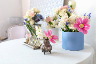 Eski vazolarda birçok farklı çiçekli masa: güller, laleler, şakayıklar ve elbise askıları. Hafif, pejmürde, şık Provence tarzı. Ev içi oda tasarımı. Estetik minimalist çiçek kompozisyonu 