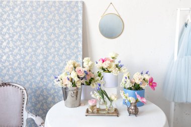 Eski vazolarda birçok farklı çiçekli masa: güller, laleler, şakayıklar ve elbise askıları. Hafif, pejmürde, şık Provence tarzı. Ev içi oda tasarımı. Estetik minimalist çiçek kompozisyonu 