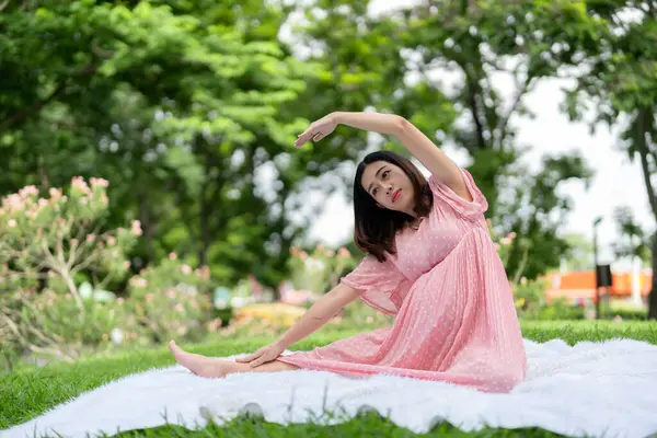 亚洲孕妇在公园做瑜伽放松的肖像 图库图片